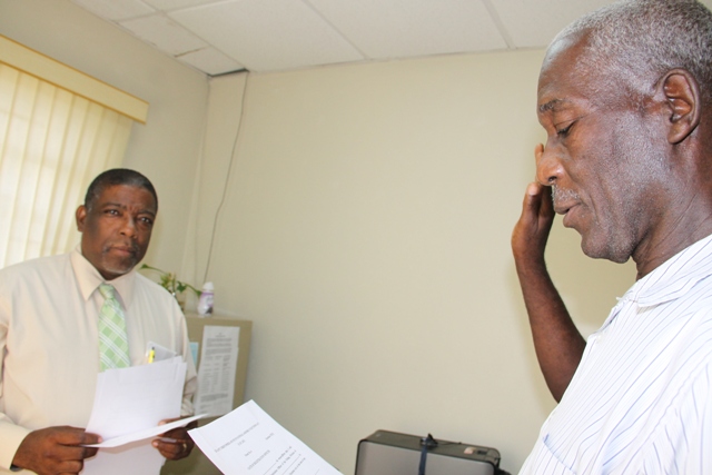 Calvin Fahie (r) being sworn in as a Registration Officer for Constituency 9 by Supervisor of Elections Elvin Bailey at the Electoral Office on Nevis on July 20, 2015